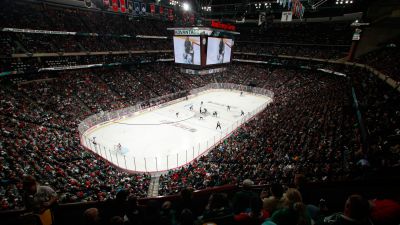 Landmark Tower A crowded ice hockey arena during a game, with players on the ice and a large screen above.