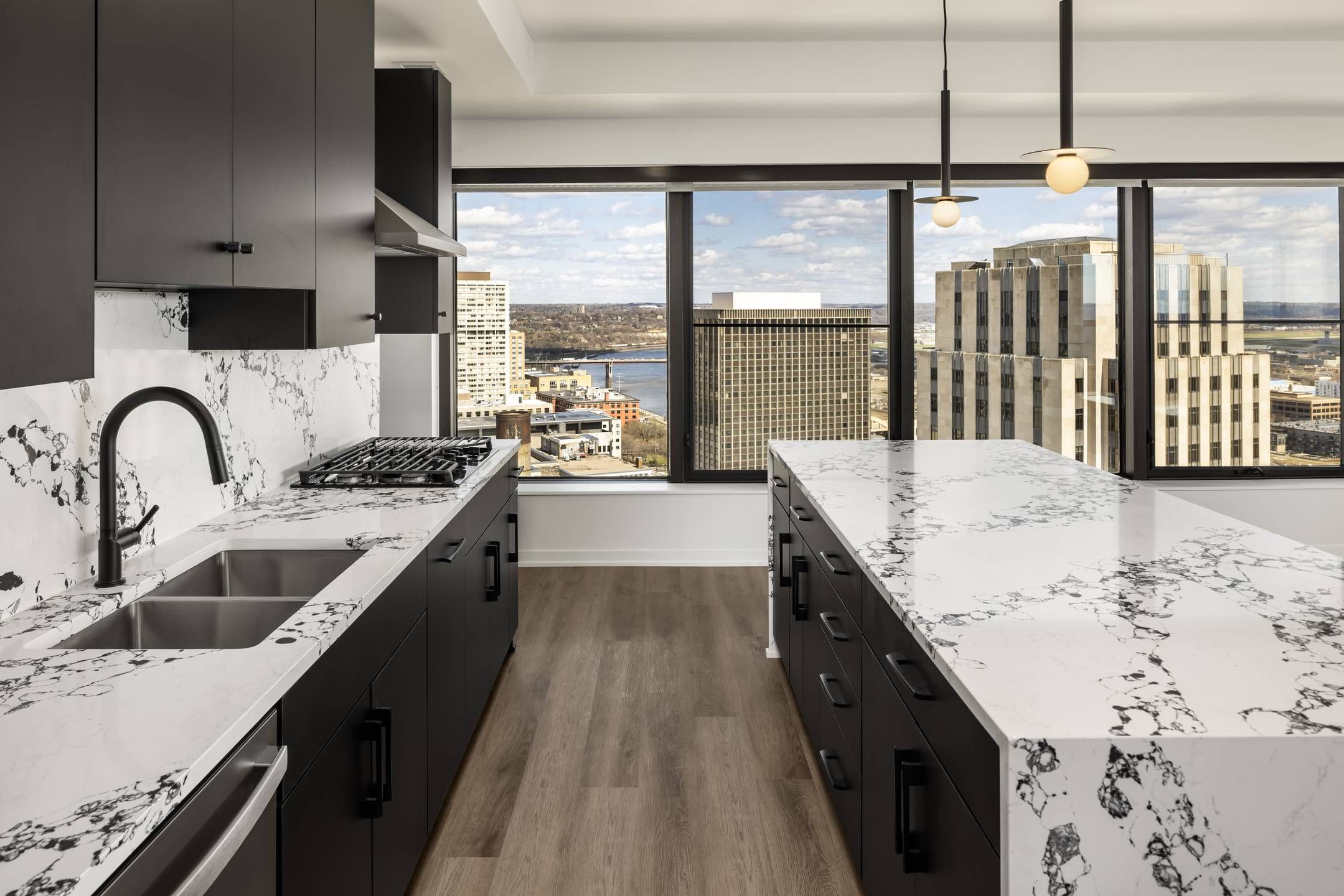 Landmark Tower apartments Modern kitchen with marble countertops, black cabinets, and large windows overlooking a cityscape.