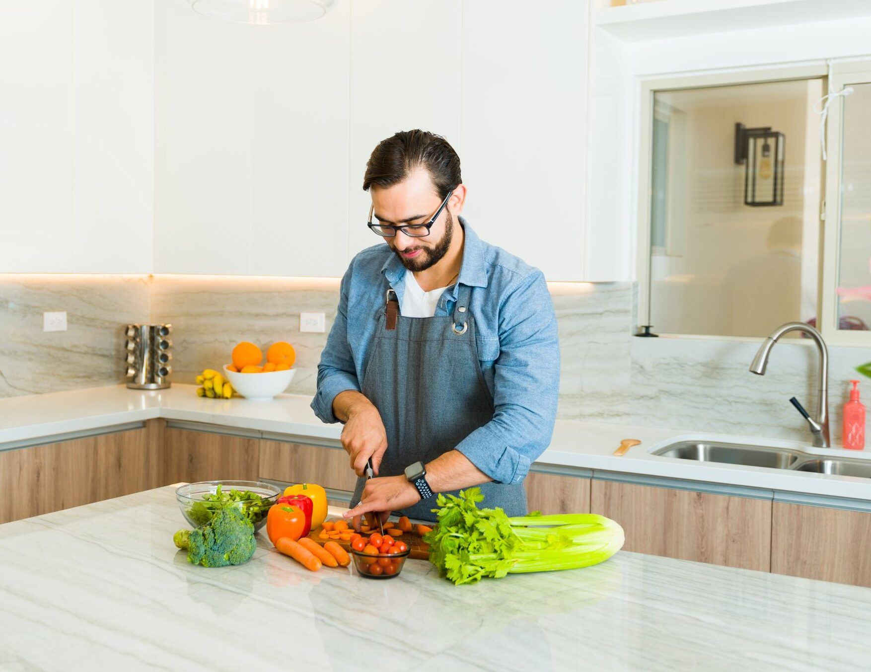 Landmark Tower Man chopping vegetables on a kitchen island with a modern design and stainless steel appliances.