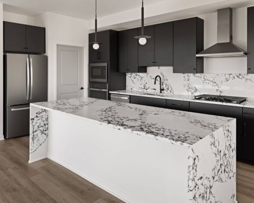 Landmark Tower apartments Penthouse Modern kitchen with black cabinets, marble countertops, stainless steel appliances, and wood flooring.