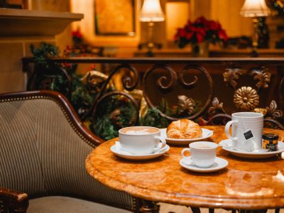 Landmark Tower A cozy café setting with a latte, croissant, tea, and honey on a marble table by an ornate railing.