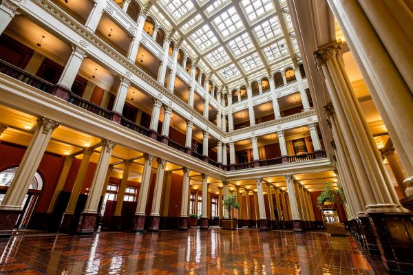 Landmark Tower Grand atrium with high ceilings, ornate columns, and warm lighting through large skylights, reflecting on a shiny floor.