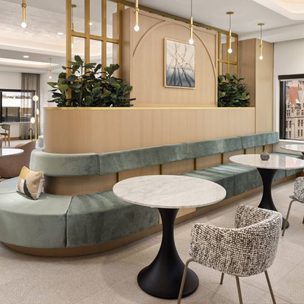 Landmark Tower apartments Modern lounge area with green velvet seating, marble tables, patterned chairs, and city view windows.