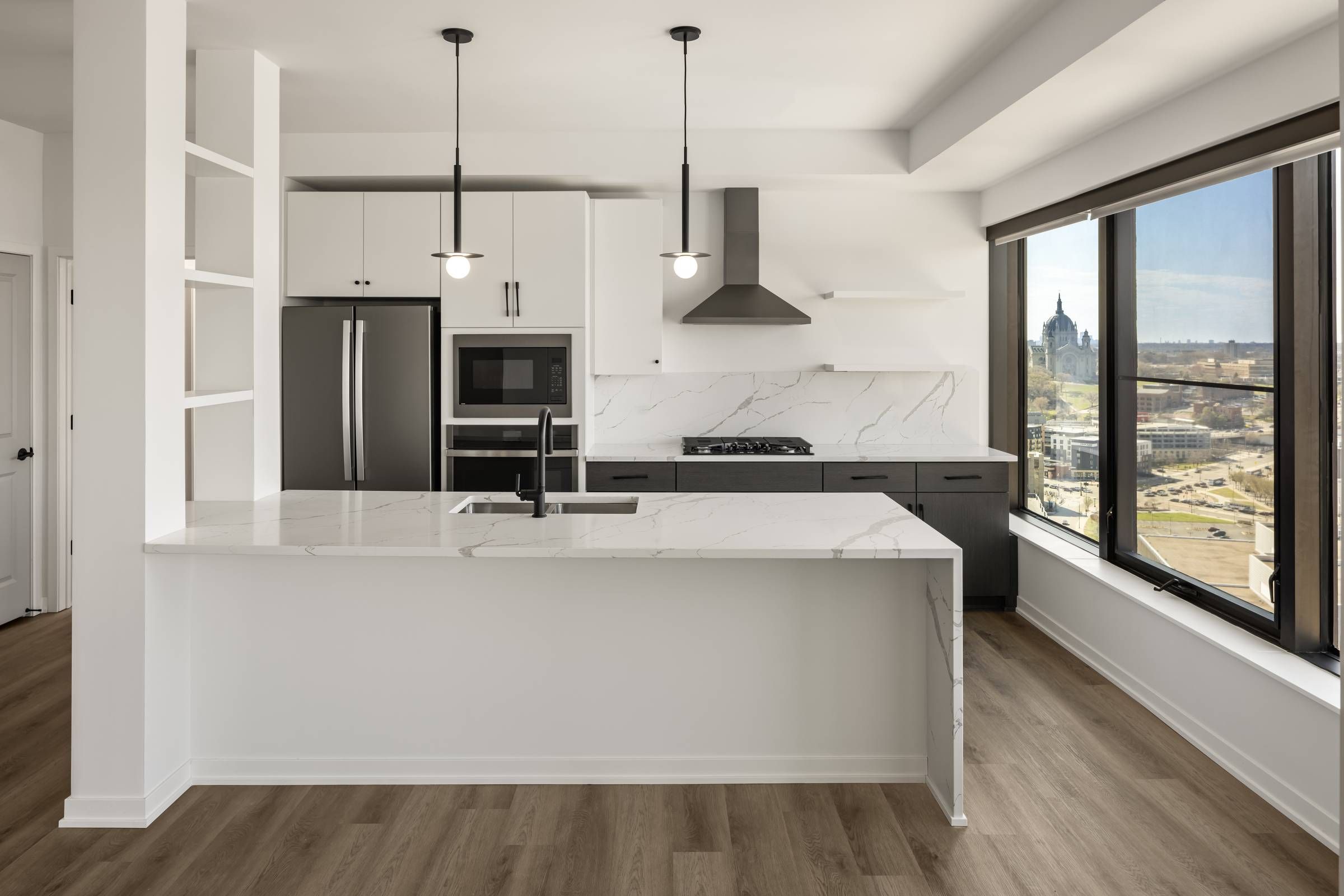 Landmark Tower Modern kitchen with white cabinetry, marble countertops, stainless steel appliances, and large window city view.