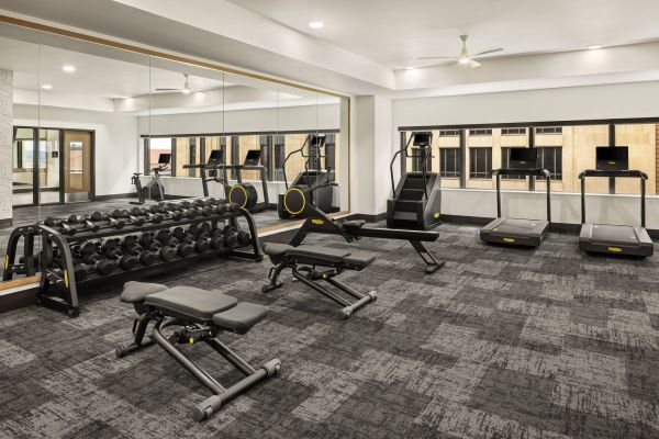 Landmark Tower apartments Modern gym with free weights, benches, treadmills, and step machines, featuring large mirrors and windows.