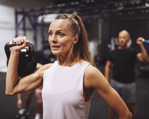 Landmark Tower Woman in a white tank top lifting a kettlebell in a gym.
