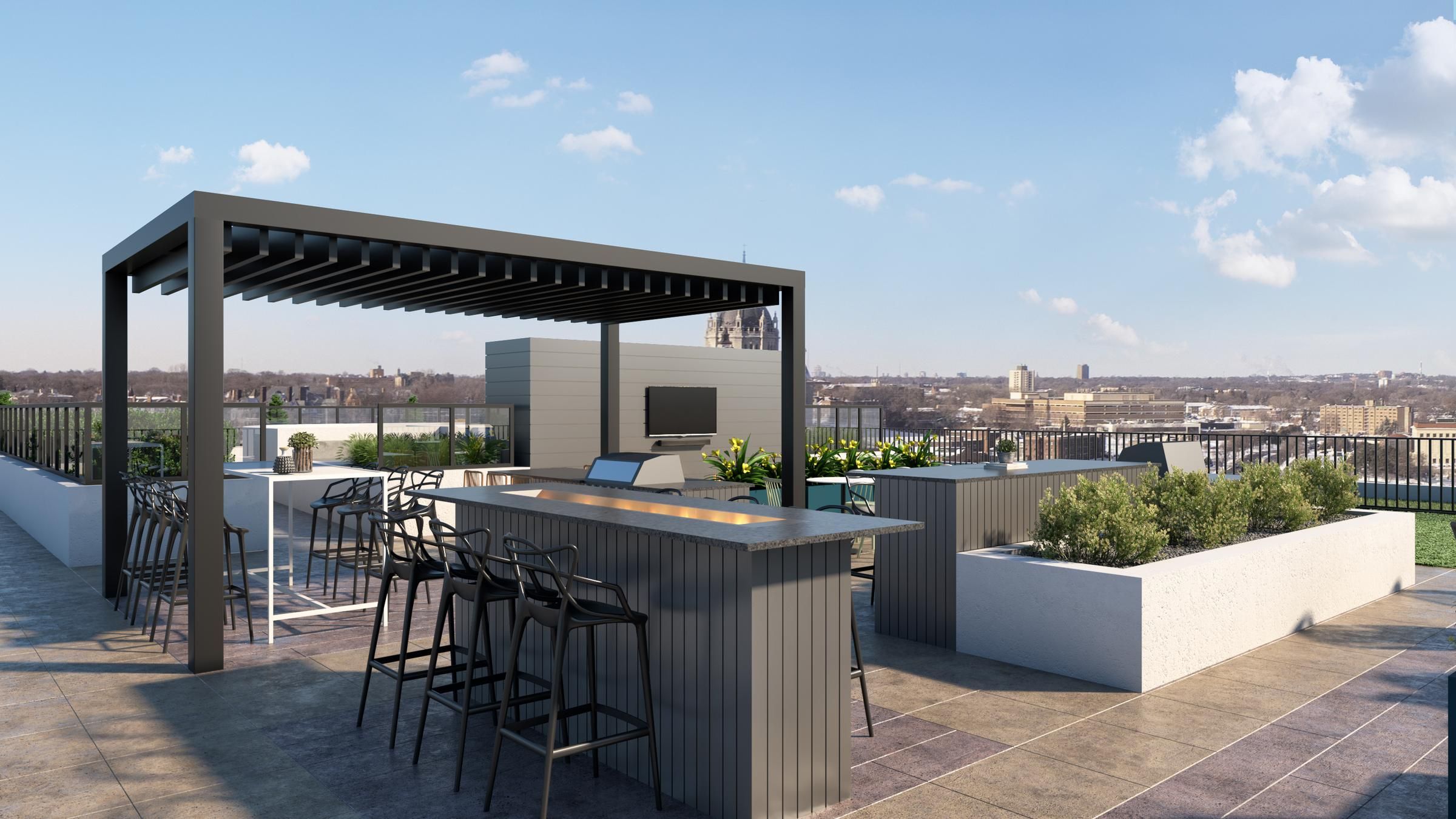 Landmark Tower Rooftop patio with a pergola, bar seating, outdoor kitchen, and city skyline in the background.