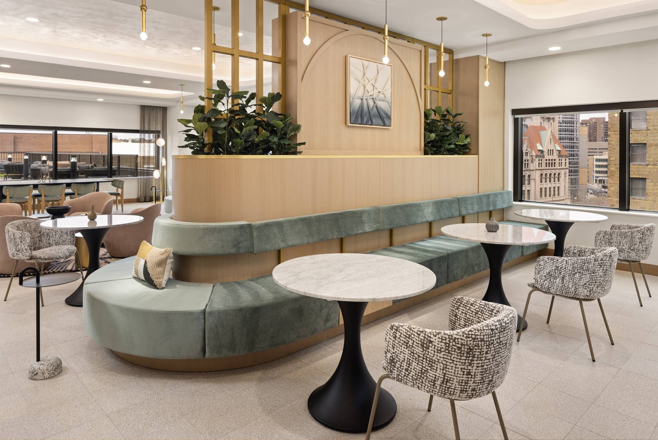 Landmark Tower apartments Modern lounge area with green velvet seating, marble tables, patterned chairs, and city view windows.