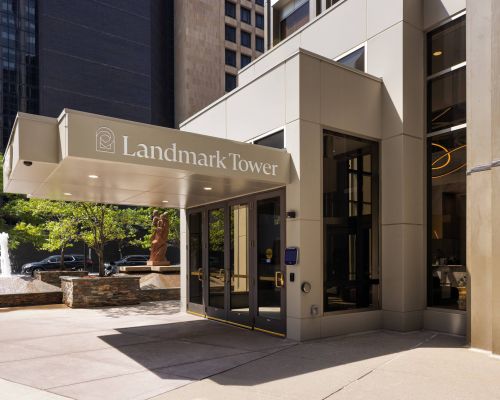 Entrance of Landmark Tower with glass doors, canopy, and fountain visible in a city setting.