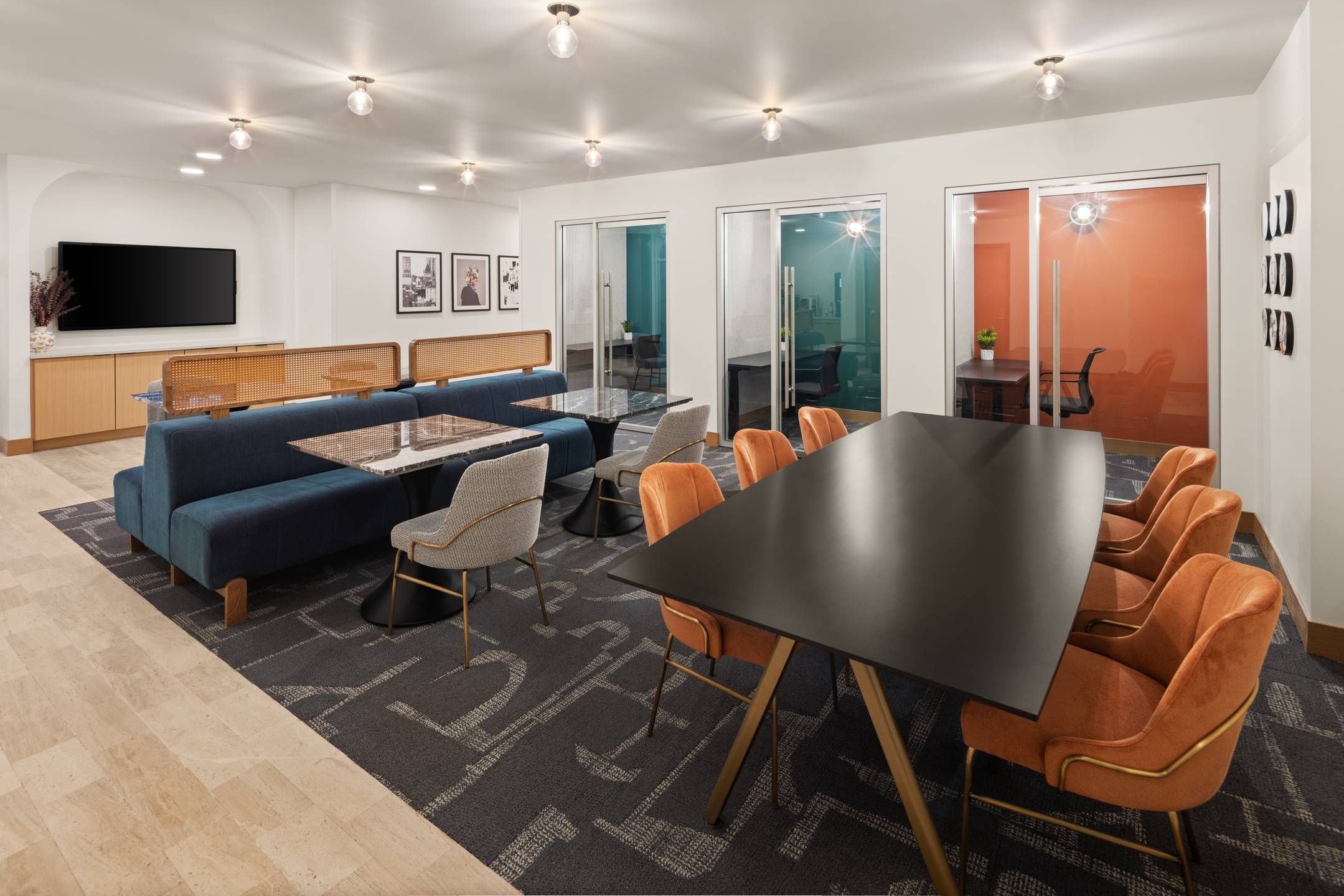 Landmark Tower apartments Modern office lounge with tables, orange chairs, blue sofa, and glass office rooms in the background.