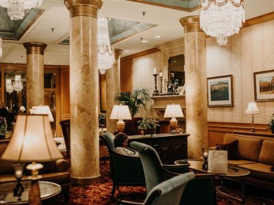 Landmark Tower Elegant hotel lobby with plush seating, marble columns, chandeliers, and framed art on walls. Warm, inviting atmosphere.