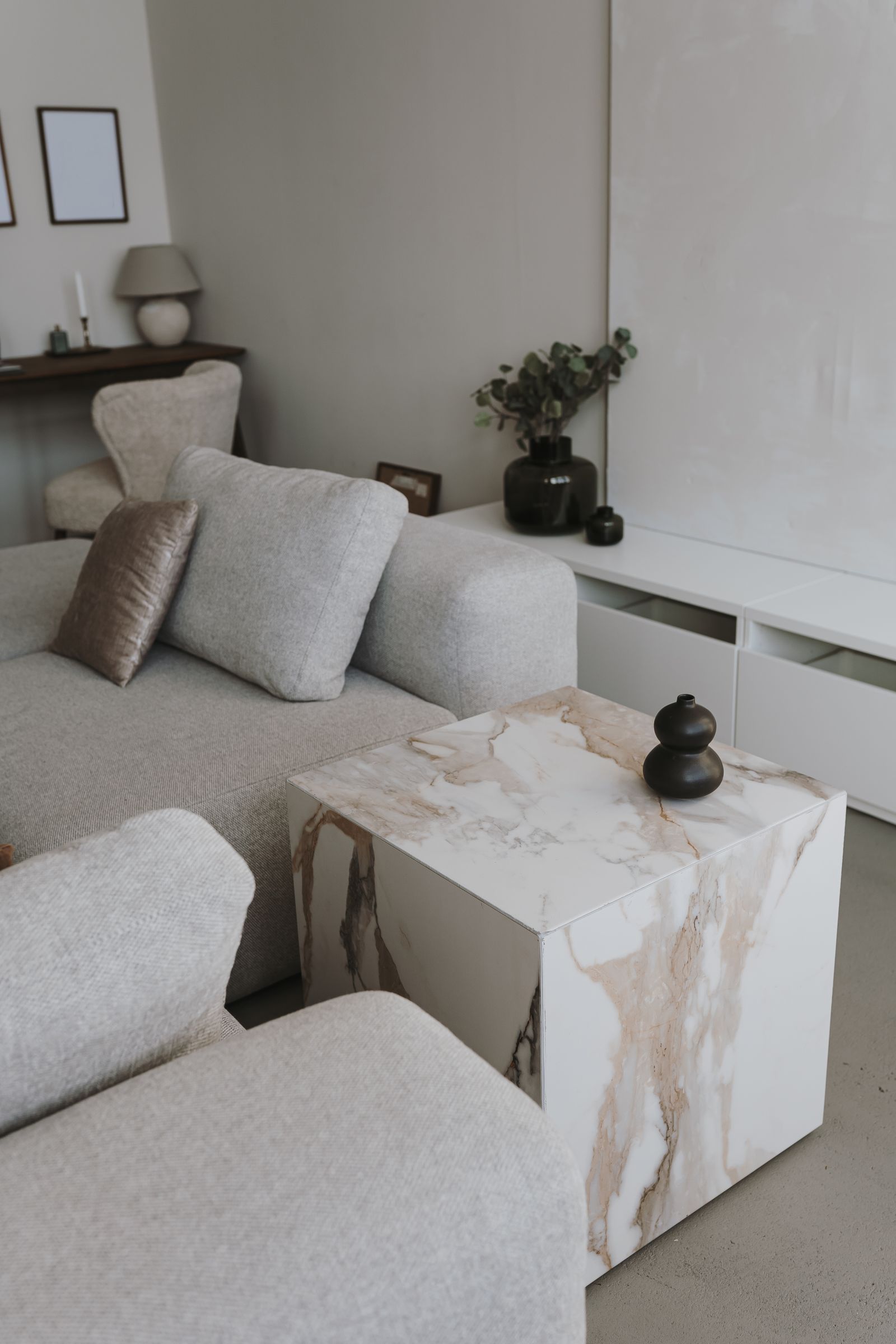 Landmark Tower Minimalist living room with a gray sofa and a marble side table. Decor includes a black vase and plants.