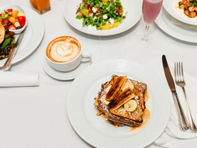 Landmark Tower Plate of banana-topped French toast, coffee, salad, and other breakfast dishes on a white tablecloth.