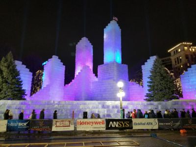 Landmark Tower Illuminated ice castle at night, colorful lights, people walking around, trees decorated with lights in the background.