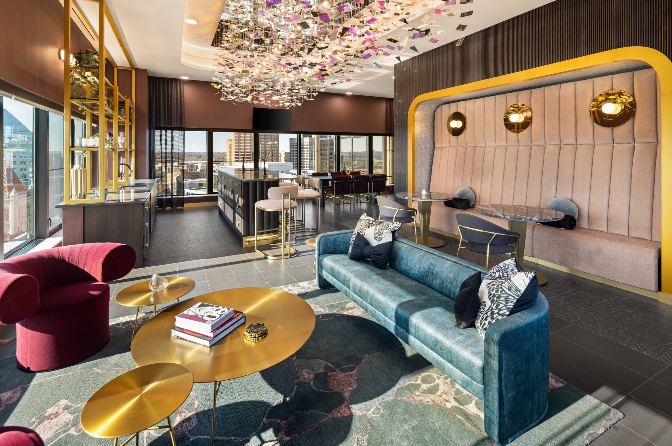 Landmark Tower apartments Modern lounge with teal sofa, gold tables, red chair, booths, and colorful ceiling decor, city view through windows.